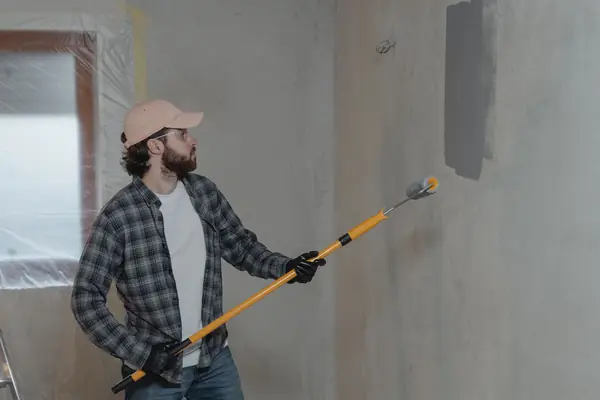 Painter rolling grey paint onto an interior wall in Tampa